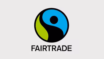 Das Fairtrade-Logo zeigt eine stilisierte schwarze Figur mit erhobenem Arm, umgeben von einem grün-blauen kreisförmigen Hintergrund. Unter dem Logo steht in fetten schwarzen Buchstaben das Wort „FAIRTRADE“.